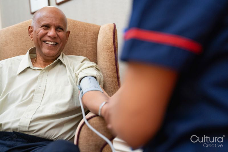 Nurse checking blood pressure of senior man in nursing home