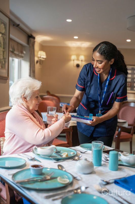 Nurse giving pill to senior lady during dinner at cafeteria in nursing home