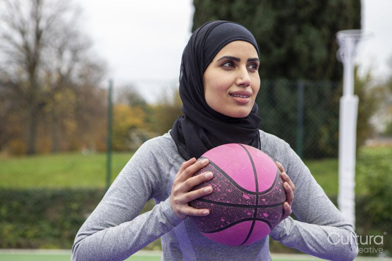 Smiling woman in hijab holding basketball ball