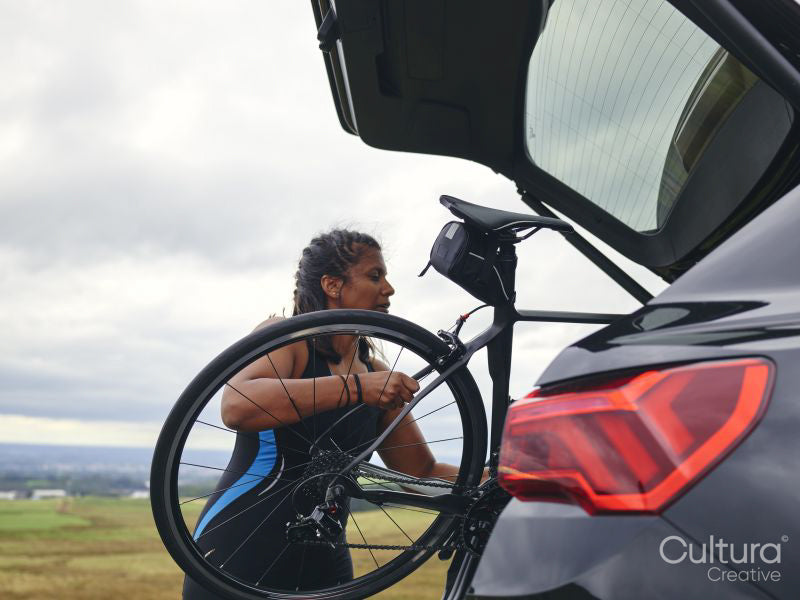 Woman taking bicycle out of car trunk