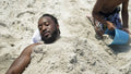 Boy covering father with sand on beach