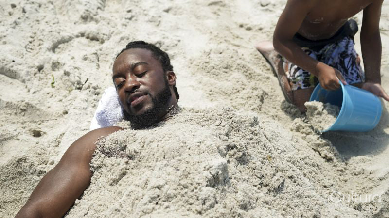 Boy covering father with sand on beach
