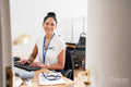 Portrait of smiling female doctor sitting at desk in office
