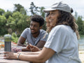 Friends laughing during picnic by lake