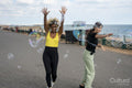 Female couple playing with soap bubbles in street