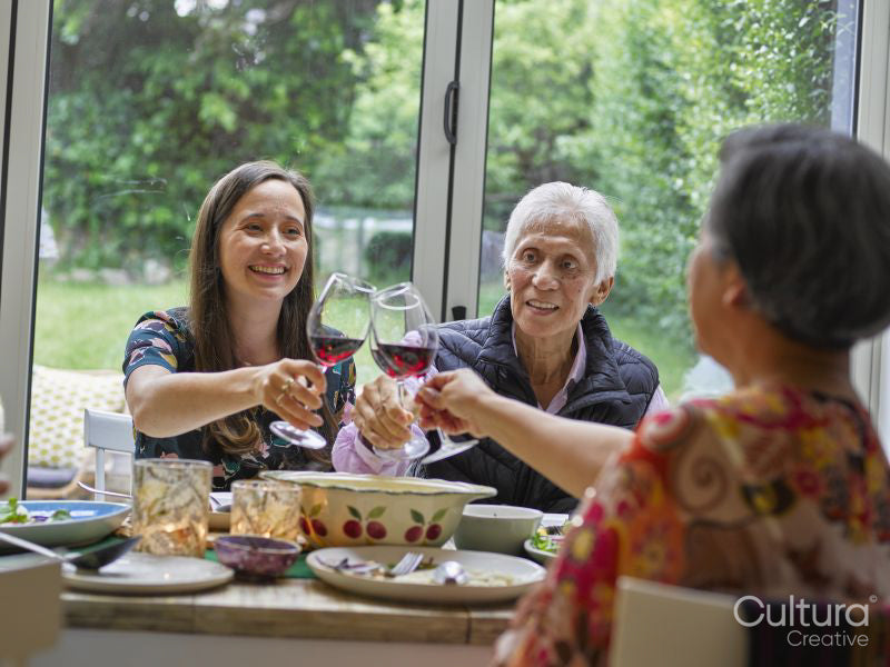 Family toasting with red wine at dinner table