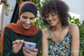 Two smiling friends looking at smart phone
