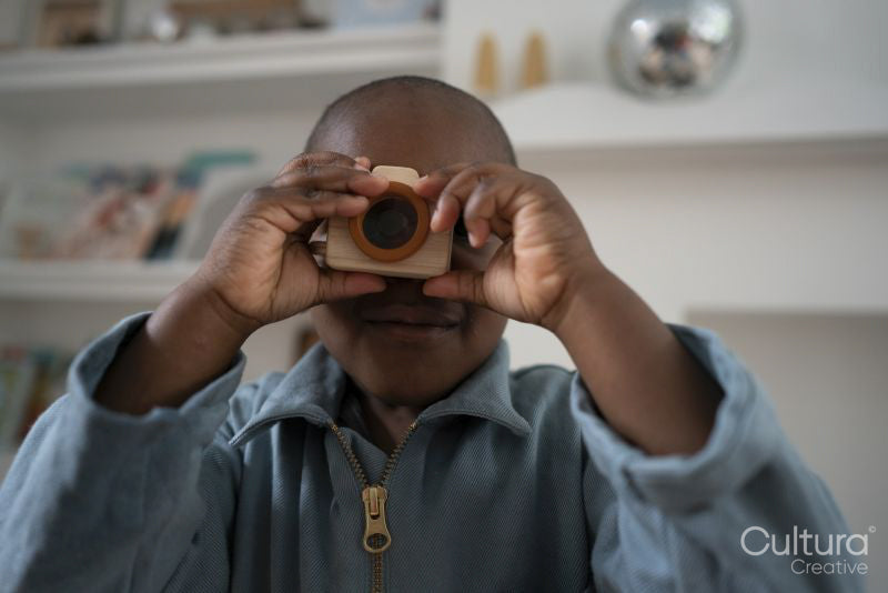 Boy playing with wooden toy camera
