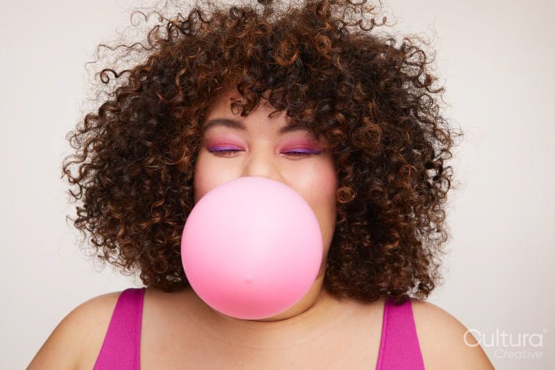 Brunette woman blowing pink balloon