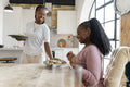 Smiling woman serving dinner for girlfriend at home