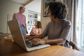 Smiling woman with laptop looking at partner and daughter at home