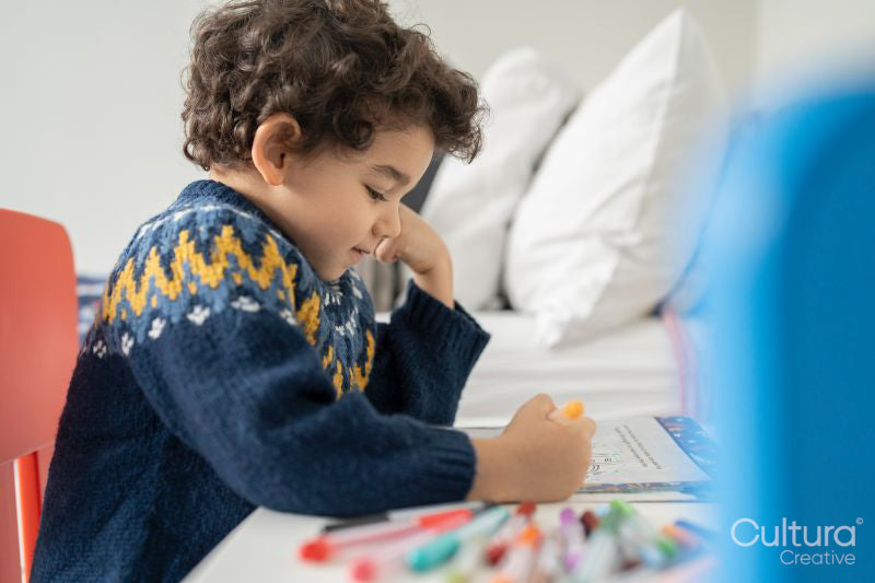 Boy coloring in coloring book at home