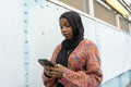 Young woman wearing hijab looking at smart phone