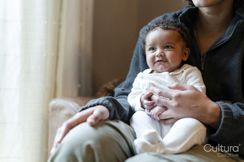 Young mother holding baby girl on lap at home