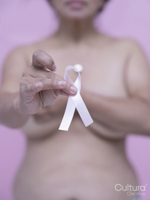 Mid section of shirtless woman with pink breast cancer awareness ribbon