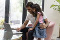 Father sitting with daughter and using laptop