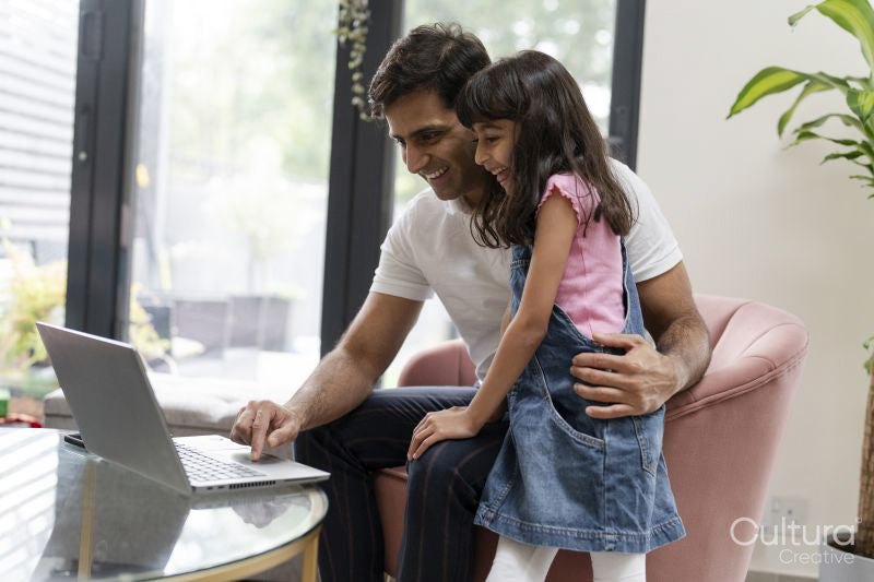 Father sitting with daughter and using laptop