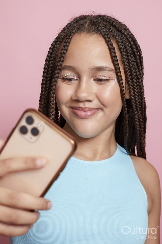 Studio shot of smiling girl with braids holding smart phone