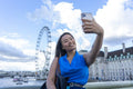 United Kingdom, London, Woman taking selfie with Millennium Wheel in background