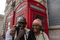 Happy mature couple posing in front of traditional red telephone booth