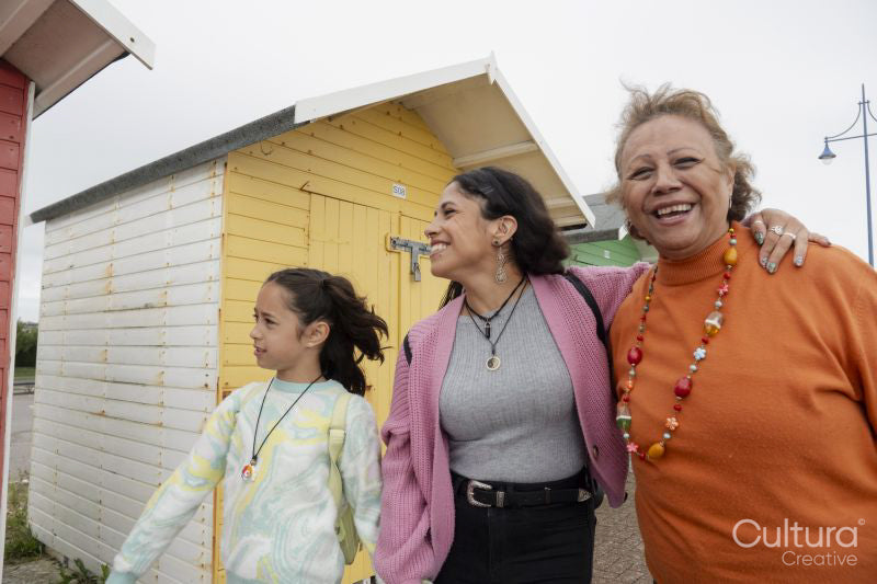 Grandmother, mother and granddaughter walking by beach hut