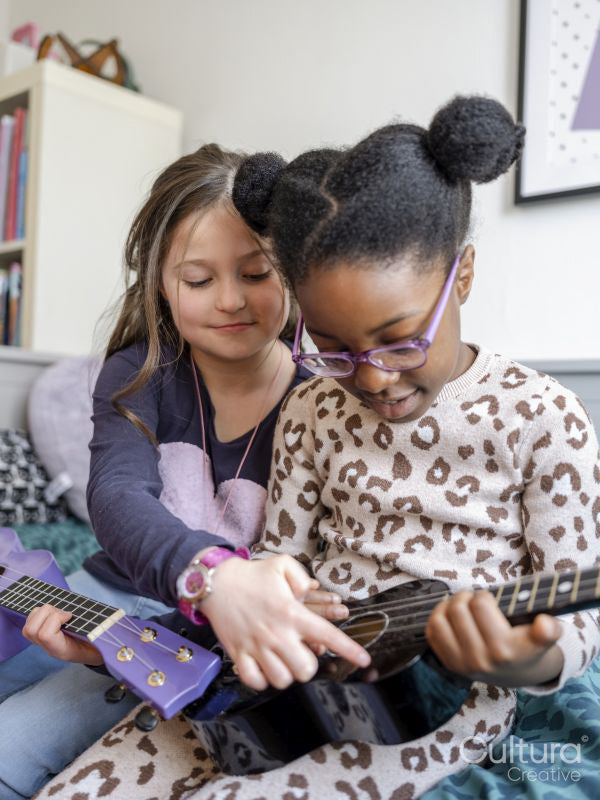 Girl friends playing ukulele at home
