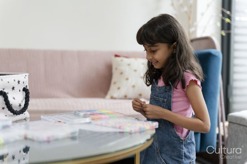 Little girl playing with beads in living room