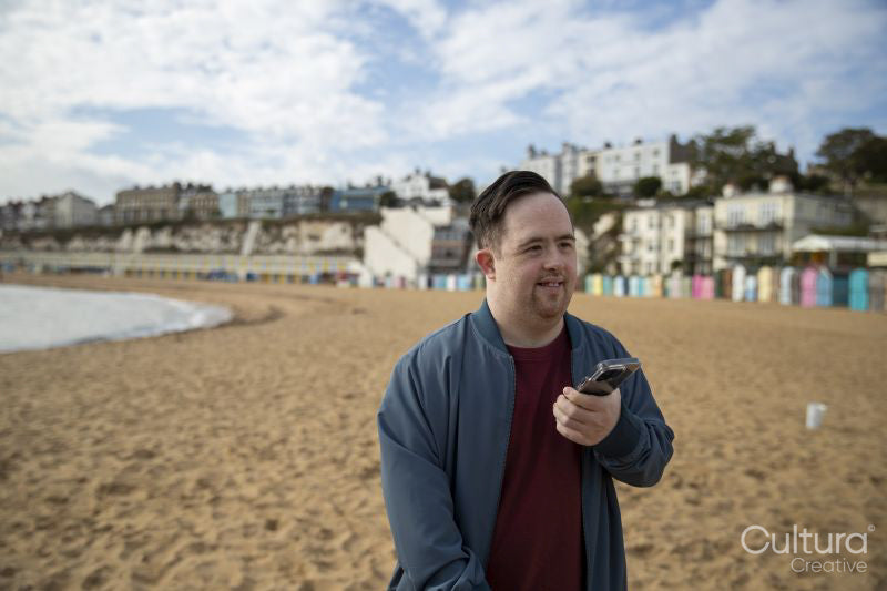 Mid adult man on beach, holding phone