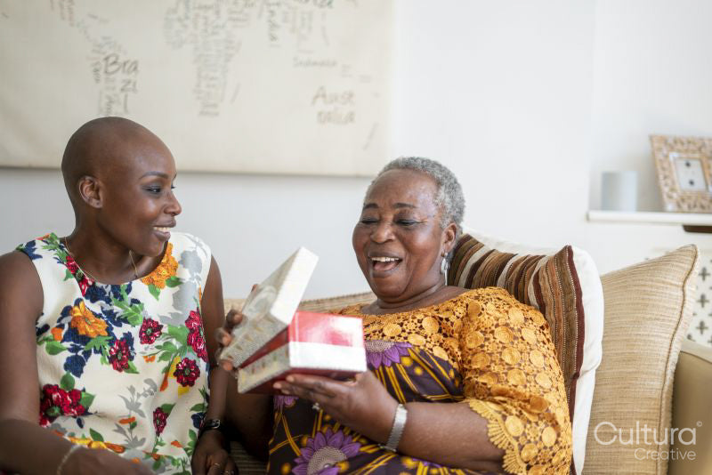 Smiling woman giving gift to mother at home
