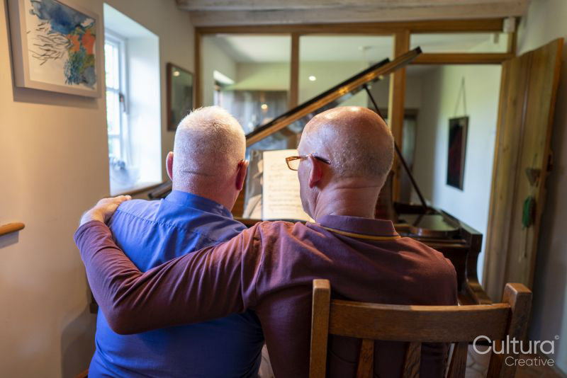 Senior male couple playing piano at home