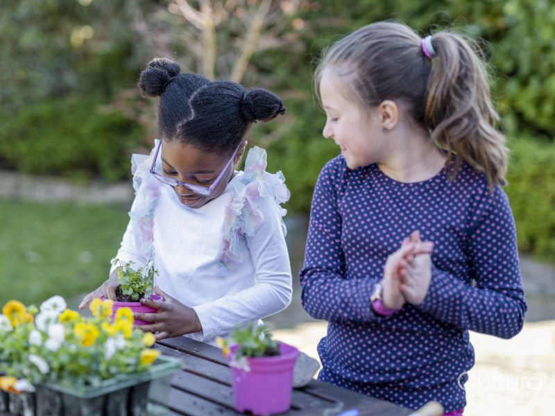 Girl friends potting plants in back yard