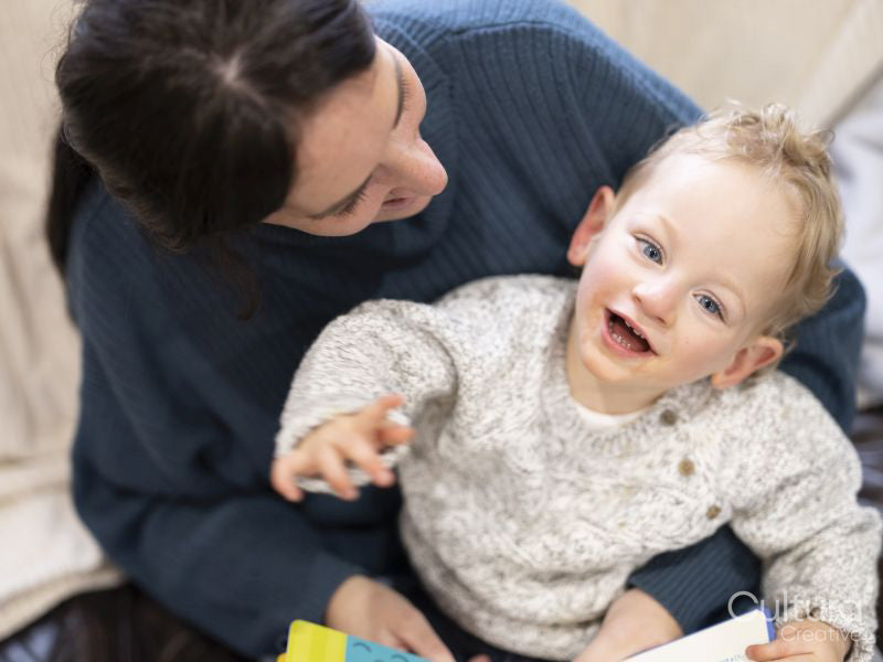 Smiling boy with cerebral palsy sitting on mothers lap