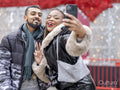 Young couple taking selfies against Christmas decorations