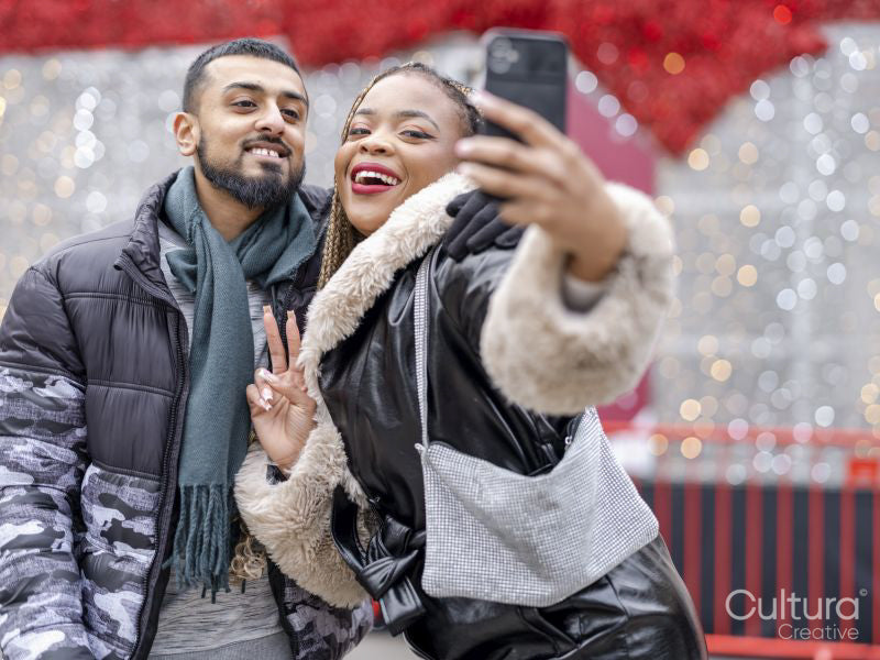 Young couple taking selfies against Christmas decorations
