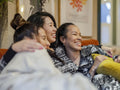 Smiling friends resting in pajamas on sofa in living room