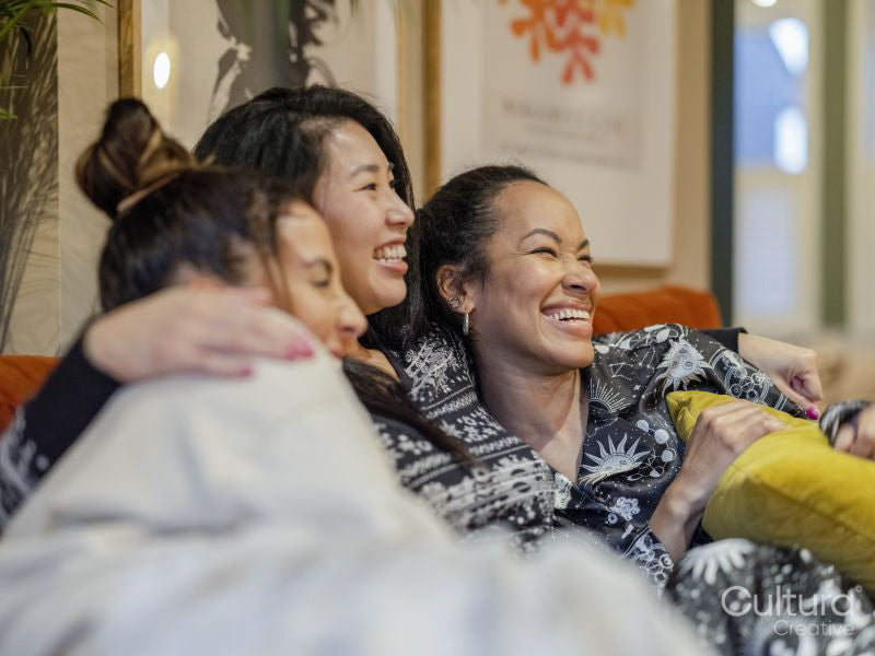 Smiling friends resting in pajamas on sofa in living room