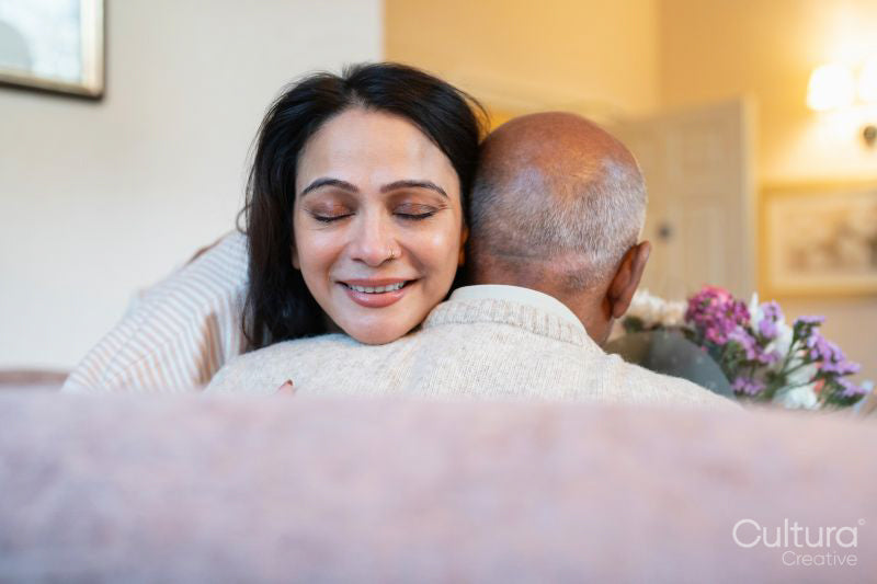 Woman hugging senior father during visit in nursing home