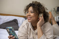 Smiling woman with headphones listening music from smart phone