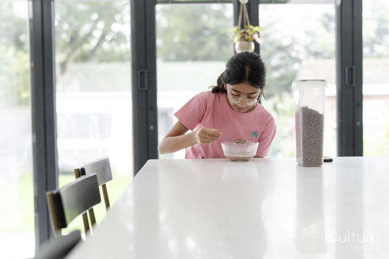 Girl eating breakfast at table in living room