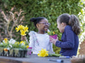 Girl friends potting plants in back yard