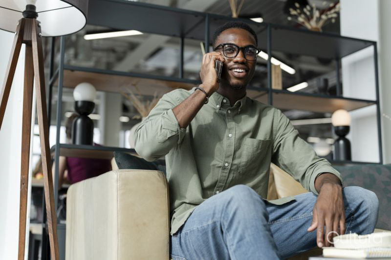 Young man with smartphone sitting in office lounge