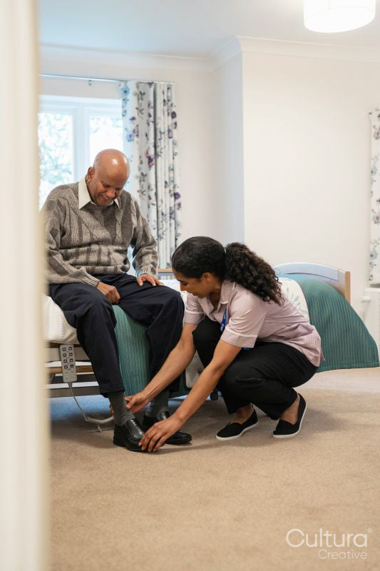 Nurse helping senior man to get dressed at nursing home