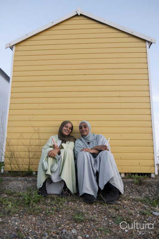 Two Muslim friends sitting by beach hut