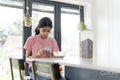 Girl eating breakfast and using phone at table in living room