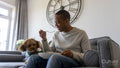 Man eating lunch on sofa, dog sitting by