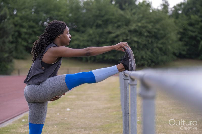 Athletic woman stretching leg on running track