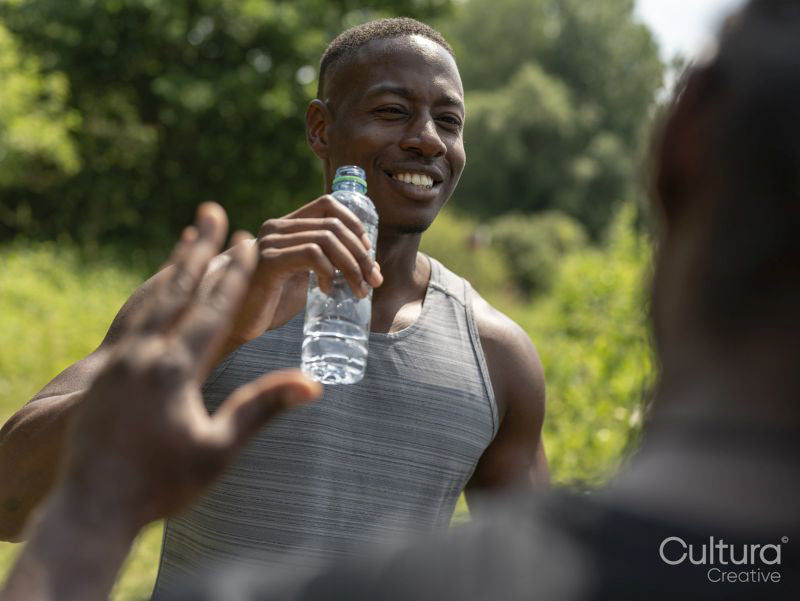 Two men drinking water after exercising outdoors