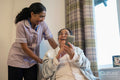 Senior lady looking at phone with nurse in room at nursing home