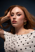 Woman in a polka dot top with windswept hair in a studio
