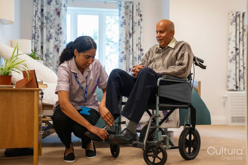Nurse helping senior man to sit on wheelchair at nursing home